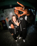 Couple in 69 black jumpsuits at night in the city | THE ONE