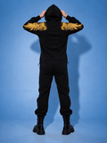 Angel black jumpsuit with hood up, back view: gold wings across the arms | THE ONE