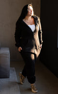 Firebird black jumpsuit unzipped with a white top: one-piece silhouette that fits | THE ONE
