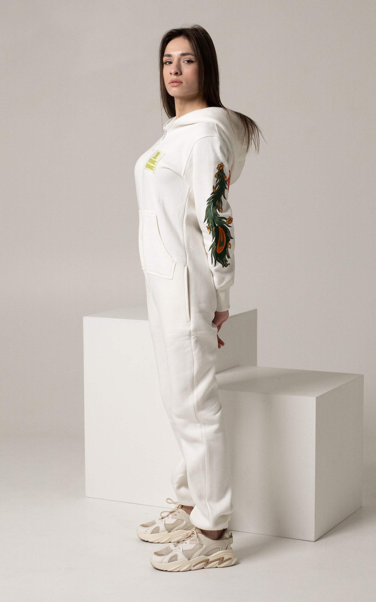 Firebird white jumpsuit on a woman, side view: embroidered sleeves | THE ONE
