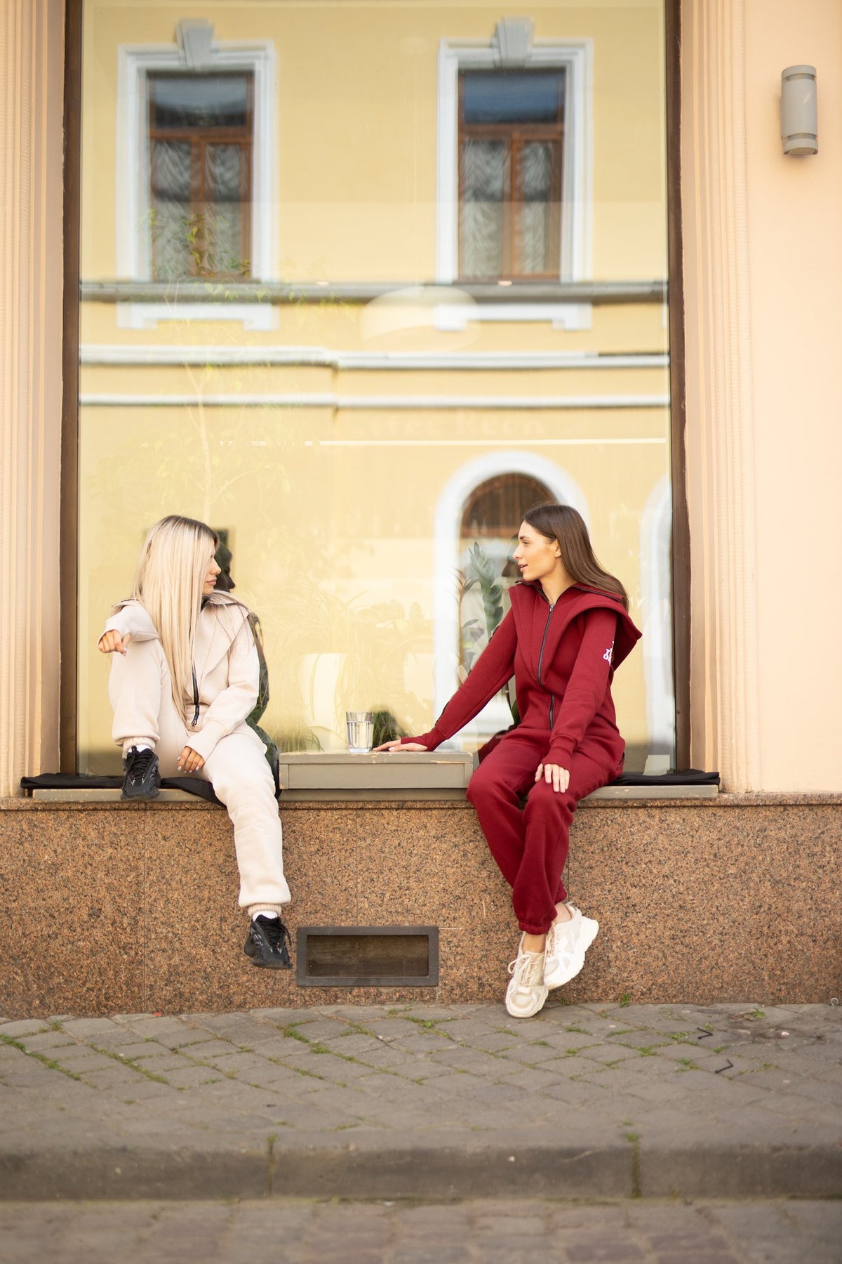 Friends in Ninja jumpsuits, wine and beige, on a city street | THE ONE